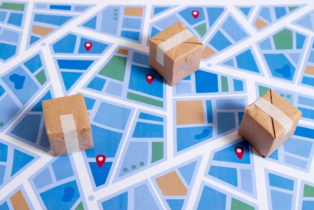 Caixas de papelão sobre um mapa ilustrado, com localizações marcadas em pontos vermelhos, representando o rastreamento de pacotes.