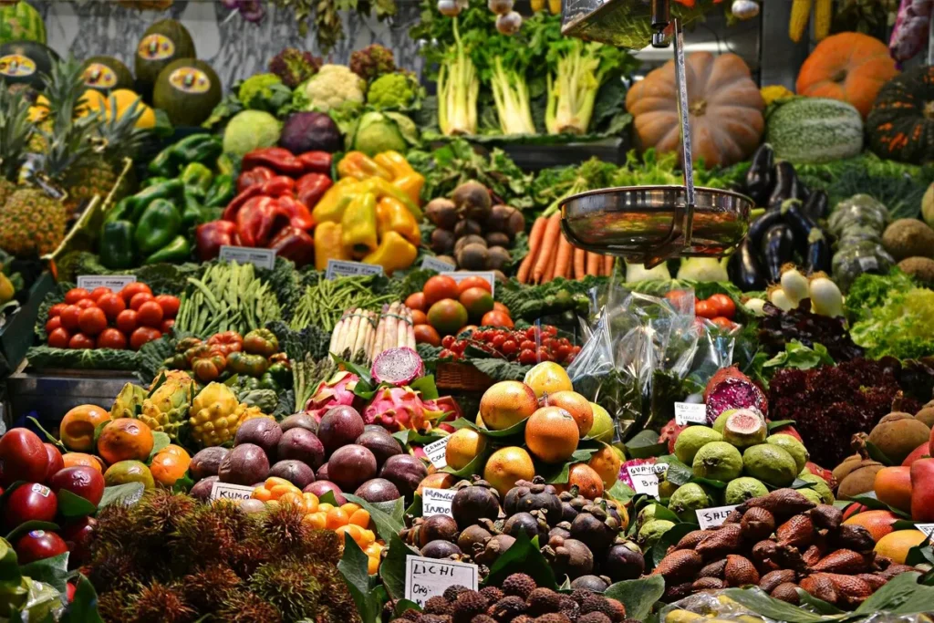 Banca de feira com grande variedade de frutas, legumes e verduras frescas organizadas em exposição