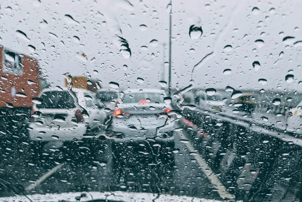 Vista do trânsito congestionado em um dia chuvoso com gotas de chuva no para-brisa
