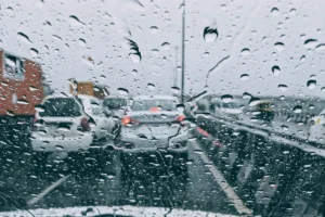 Vista do trânsito congestionado em um dia chuvoso com gotas de chuva no para-brisa