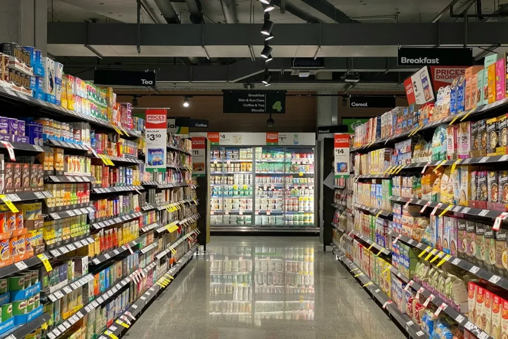 Corredor de supermercado com prateleiras repletas de alimentos não perecíveis embalados