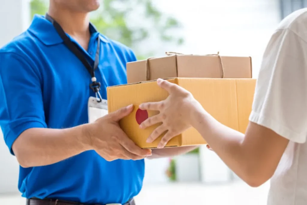 Entregador uniformizado entregando caixas a cliente, simbolizando o processo logístico e a importância do seguro de carga.