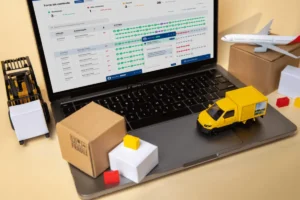 Cenário em miniatura da cadeia de suprimentos, com um caminhão de entrega em uma estrada de papel, um navio de carga em um mar de papel e miniaturas de caixas e edifícios.
