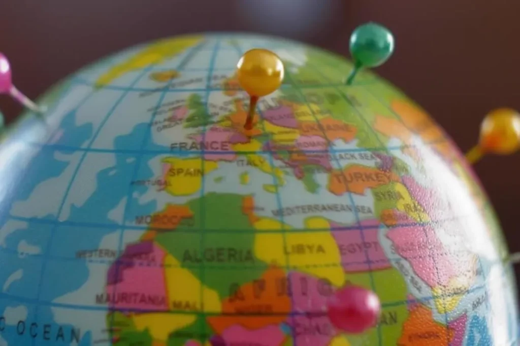 Globo terrestre com alfinetes coloridos marcando diferentes países, representando conexões comerciais internacionais.