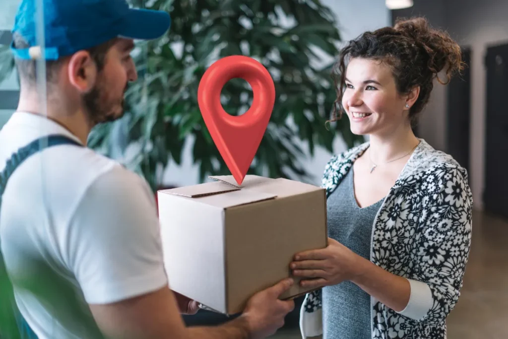 Entregador feliz entregando uma encomenda a uma cliente com o ícone de localização (pin) flutuando sobre a caixa, representando o rastreamento no modelo de dropshipping.