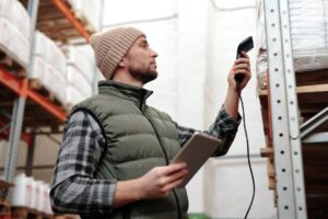 Operador usando scanner IoT e tablet para monitoramento de cargas em armazém logístico