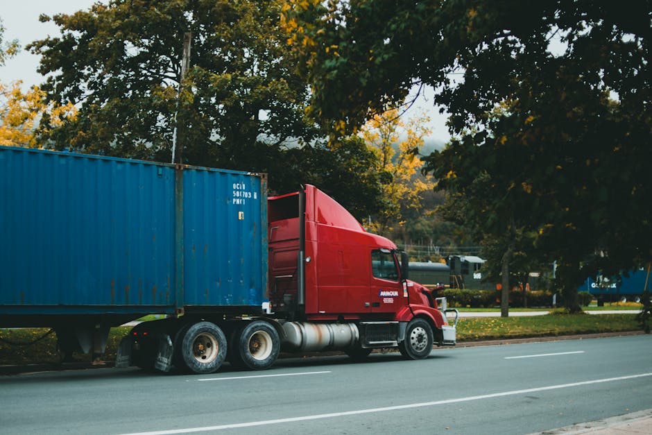 Caminhão transportando container por rodovia arborizada no trecho rodoviário do frete multimodal