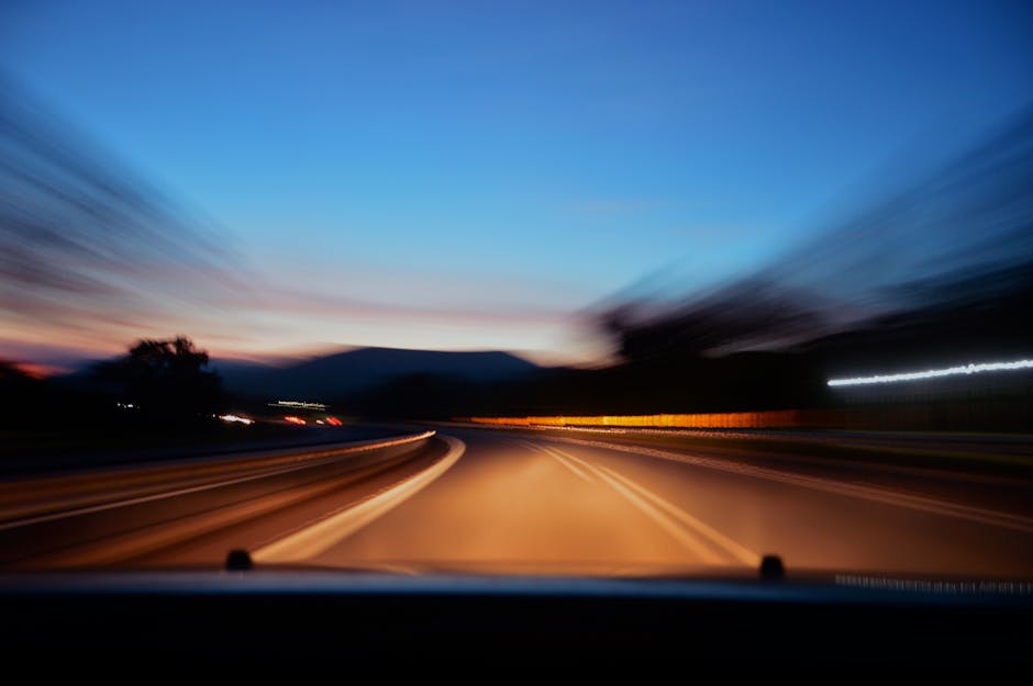 Blurred highway scene with car lights at twilight, showcasing motion and speed.