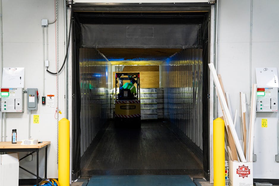Empilhadeira descarregando mercadorias em doca de carregamento dentro de armazém