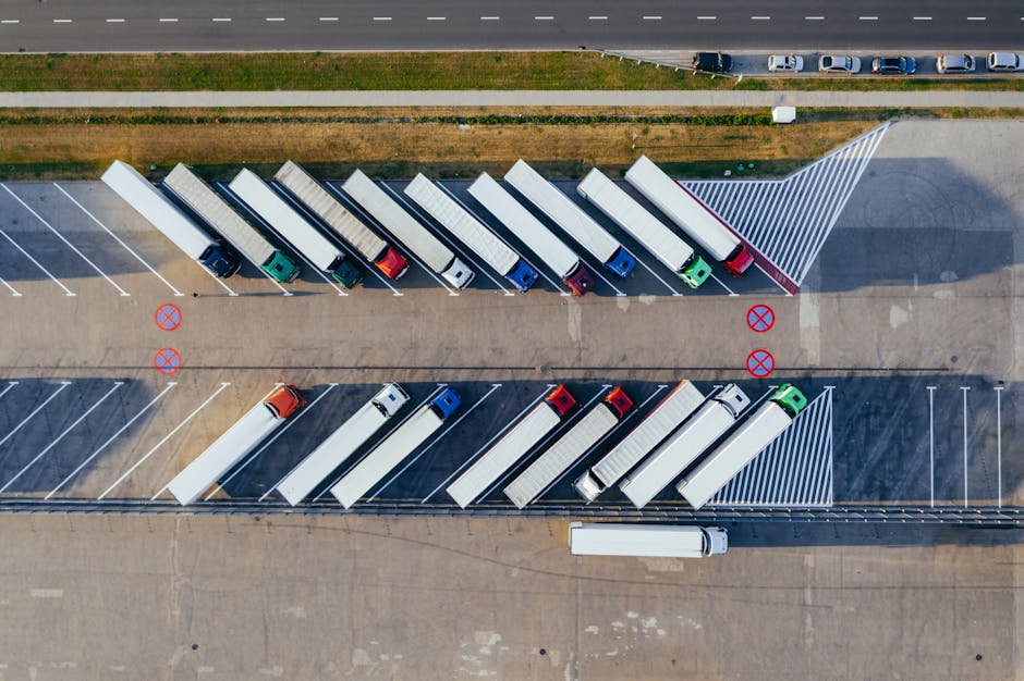 Vista aérea de caminhões estacionados em pátio logístico representando frota própria tradicional