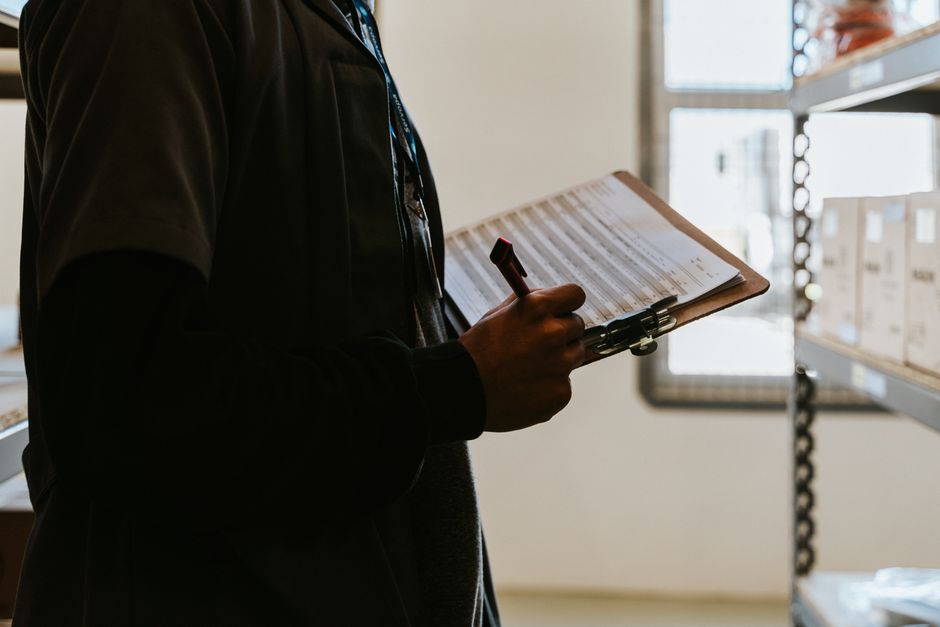 Profissional conferindo checklist de controle de qualidade em armazém logístico