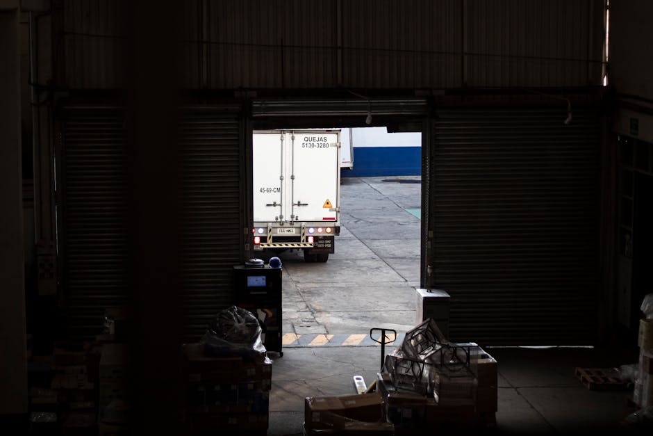 Caminhão de entregas saindo de doca de carregamento em armazém de distribuição atacadista