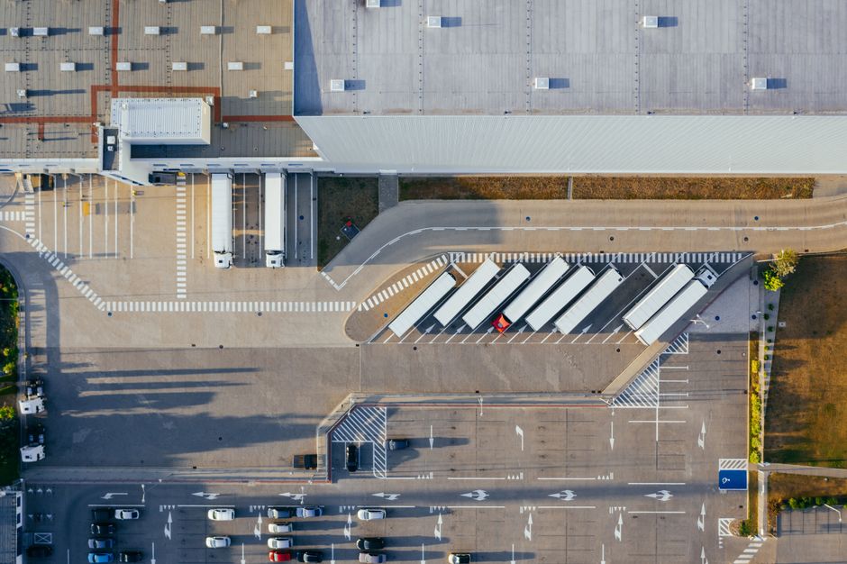 Vista aérea de centro de distribuição logístico com caminhões e docas de carga